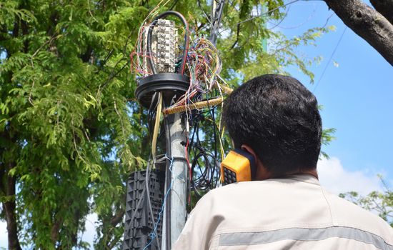 technician is plugging in a network cable to the line socket.