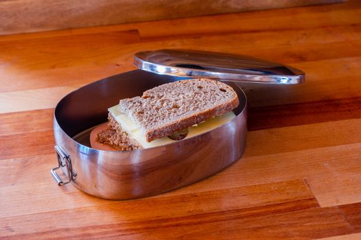 school lunch packed in stainless steel lunchbox on wooden surface