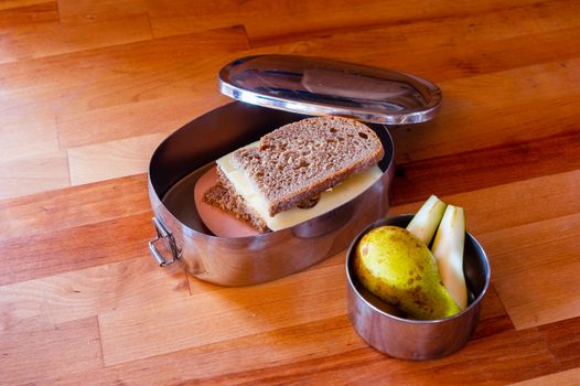 school lunch packed in stainless steel lunchbox on wooden surface