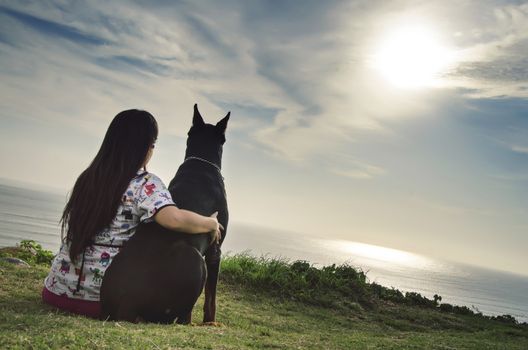 A woman and her dog watching the sunset