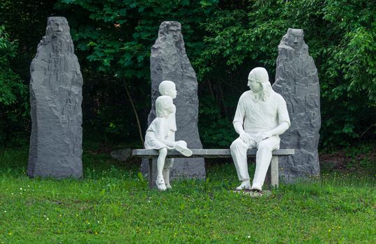 Statue of Nikolaus Ludwig, Reichsgraf von Zinzendorf und Pottendorf teaching children while sitting on a stone bench in a park.