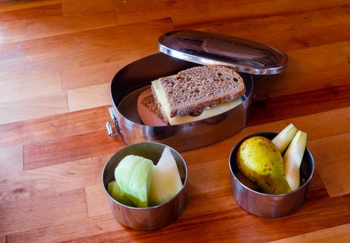 school lunch packed in stainless steel lunchbox on wooden surface