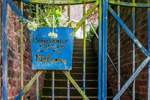 Welcome sign on old gate in english and french