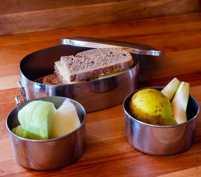 school lunch packed in stainless steel lunchbox on wooden surface