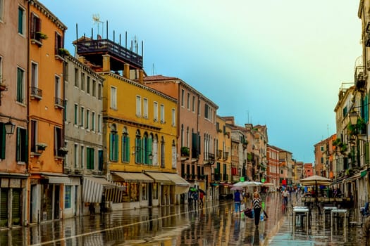 Old street with small colorful houses in the rain. Garibaldi street. Venice, Italy