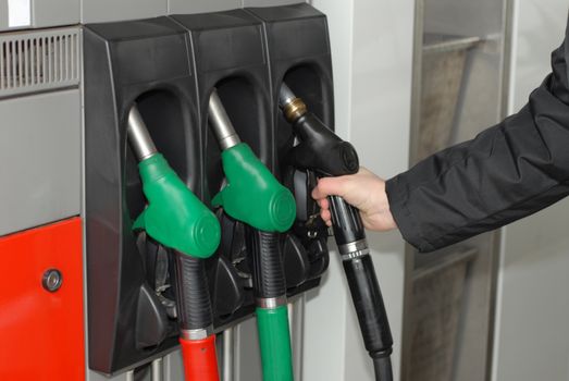 Close-up of a men's hand using a fuel nozzle at a gas station