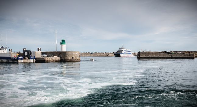 Ile d Yeu, France - September 16, 2018: ferry that enters the harbor of the island of Yeu where travelers are sitting to admire the show on a summer day