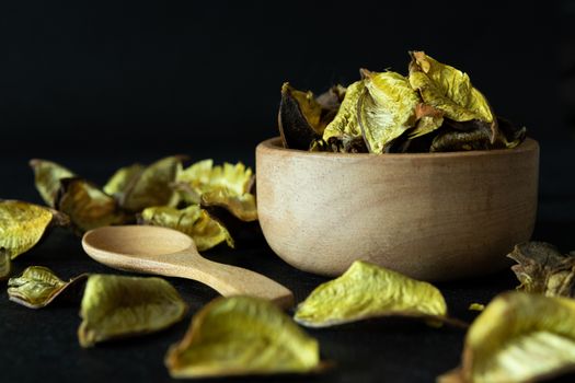 Golden dried leaves Herbs in a wooden bowl Placed on a black background