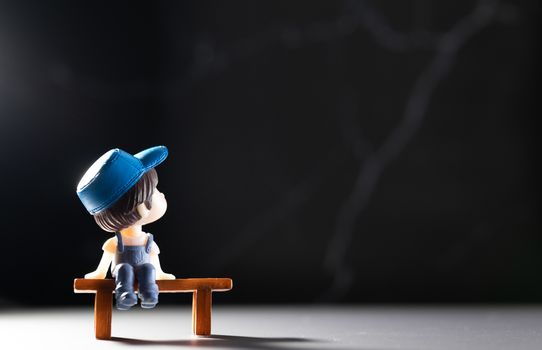 A small cartoon man sitting on a wooden table alone To wait or Demonstrated the idea of ​​a distant society to avoid the spread of coronary viruses or other contagious diseases