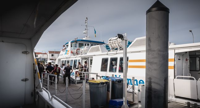 Ile d Yeu, France - September 16, 2018: ferry that enters the harbor of the island of Yeu where travelers are sitting to admire the show on a summer day