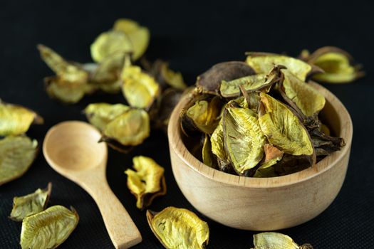 Golden dried leaves Herbs in a wooden bowl Placed on a black background