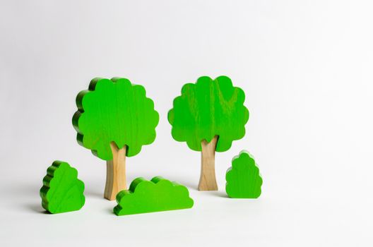 Wooden figures of trees and bushes on a white background. The concept of forests and nature. Preserving the environment from human influence. Illegal deforestation. Restoration of natural habitats.