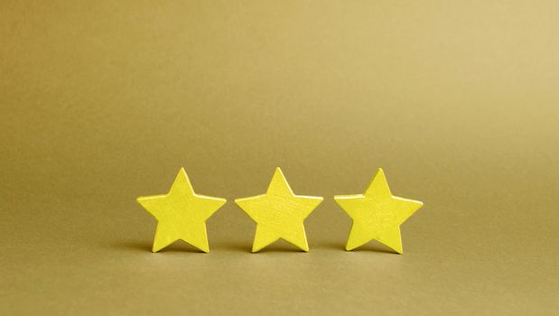 Three golden stars on a yellow background. Quality service, buyer choice. Success in business. The concept of rating and evaluation. The rating of the hotel, restaurant, mobile application.