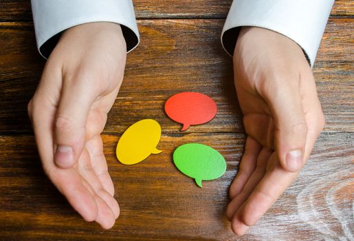 A man collects multicolored speech bubbles in his hands. Listen to other opinions and points of view, accepting criticism and comments. Reverse contact with customers and buyers. Freedom of speech.