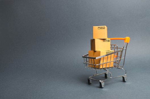 A pile of cardboard boxes in a supermarket trolley. concept of shopping in the online store . E-commerce, sales and sale of goods through online trading platforms. Consumer society. Purchasing power