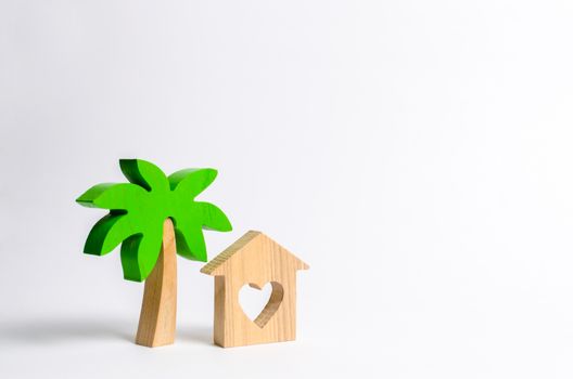 Wooden palm tree and house with hearts on a white background. Conceptual leisure and vacation. Rental homes and properties in the resort. Romantic travel. Entertainment and relaxation.