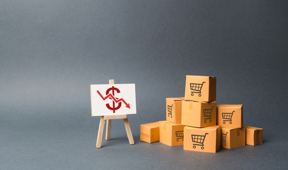 A pile of cardboard boxes and stand with a red down arrow. decline in the production of goods and products, the economic downturn and recession. Falling consumer demand, Falling prices, lower profits