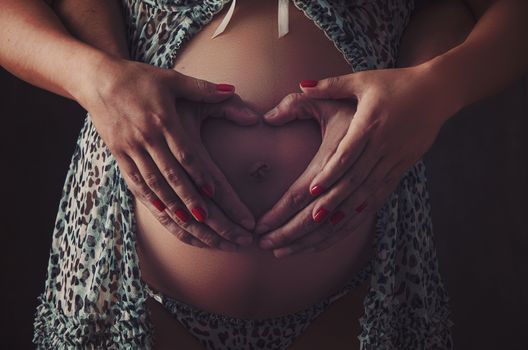 Cropped image of beautiful pregnant woman hugging the tummy