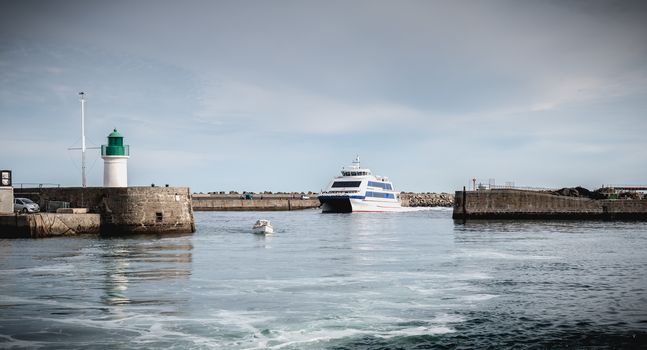 Ile d Yeu, France - September 16, 2018: ferry that enters the harbor of the island of Yeu where travelers are sitting to admire the show on a summer day