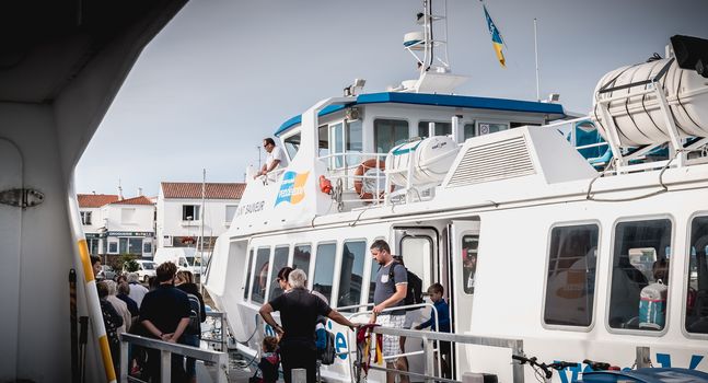 Ile d Yeu, France - September 16, 2018: ferry that enters the harbor of the island of Yeu where travelers are sitting to admire the show on a summer day