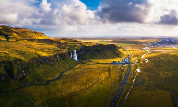 Aerial view of Seljalandsfoss Waterfall, Seljalands River, waterfall parking and the ring road in Iceland at sunset.