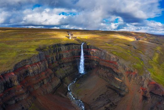Aerial view of the Hengifoss waterfall in East Iceland. Hengifoss is the third highest waterfall in Iceland and is surrounded by basaltic strata with red layers of clay between the basaltic layers.