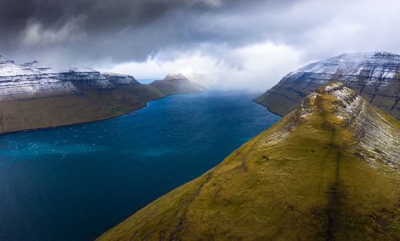 Aerial view of the island of Kalsoy and the Klakkur mountain near the city of Klaksvik on Faroe Islands with dramatic clouds.