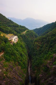 View from the Contra Dam over a hydroelectric power plant on the Verzasca River in Ticino, Switzerland. This dam is also known as the Verzasca Dam and the Locarno Dam.