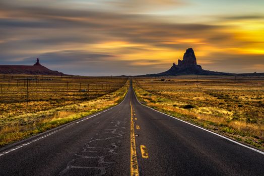 Sunrise over empty straight road leading to Monument Valley, Utah, USA. Long exposure.