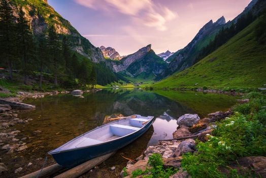 Sunset over the Seealpsee lake and the Grenzchopf mountain in the Appenzell region of Swiss Alps, Switzerland, with a boat in the foreground. Long exposure.