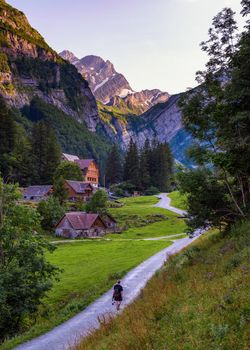 Tourist walks down the path to Seealpsee lake and the Grenzchopf mountain in the Appenzell region of Swiss Alps.