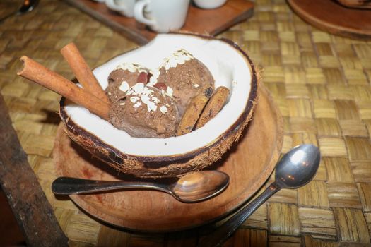 Chocolate ice cream served in fresh coconut with flesh. Sweet dessert with cocoa cookies, , banana slices and pieces of cinnamon. Delicious delicious dessert suitable as refreshment on summerer days.