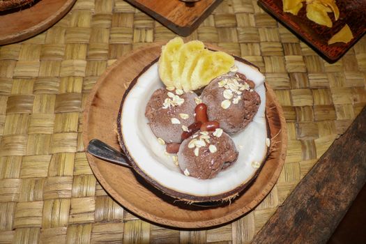 Chocolate ice cream served in fresh coconut with flesh. Sweet dessert with cocoa cookies, , banana slices and pieces of cinnamon. Delicious delicious dessert suitable as refreshment on summerer days.
