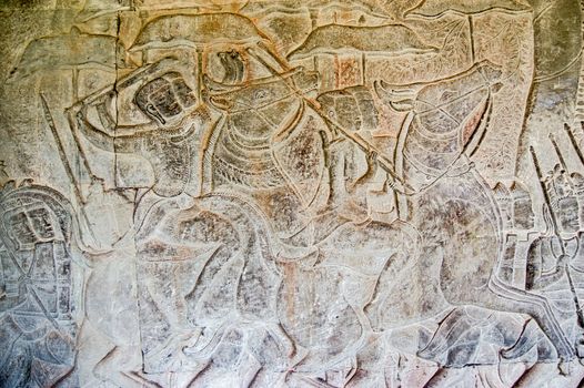 Ancient bas relief carving of cavalry soldiers waving their weapons in battle. Southern gallery of Angkor Wat Temple, Siem Reap, Cambodia. Carved in twelfth century.