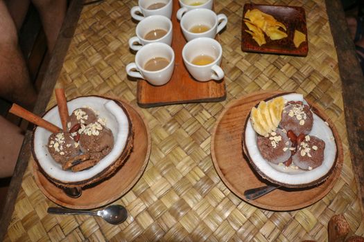 Chocolate ice cream served in fresh coconut with flesh. Sweet dessert with cocoa cookies, , banana slices and pieces of cinnamon. Delicious delicious dessert suitable as refreshment on summerer days.