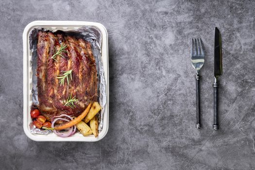 Grilled pork ribs with Vegetables and sauces on a drak table.