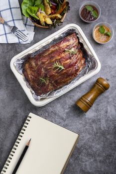 Closeup of pork ribs grilled with BBQ sauce and caramelized in honey with Vegetables and sauces on a drak table, prepared food.