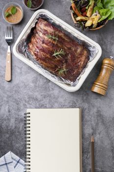 Closeup of pork ribs grilled with BBQ sauce and caramelized in honey with Vegetables and sauces on a drak table, prepared food.