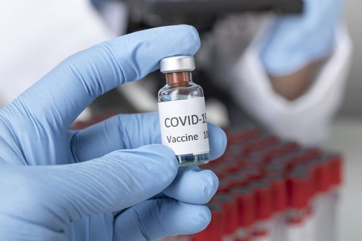 Hand holds Coronavirus Covid-19 Vaccine glass bottle. Healthcare And Medical concept.