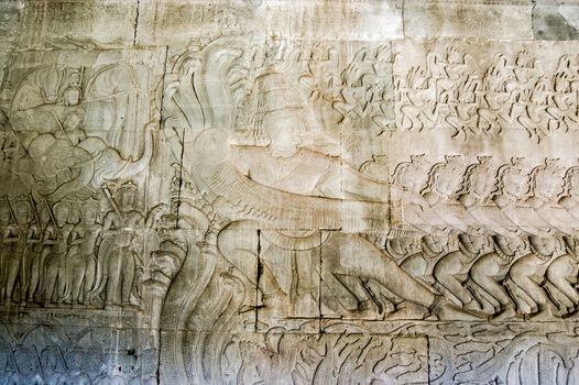 Historic Khmer carving showing the demons pulling on the sacred multi-headed snake known as Vasuki. Hindu legend, the Churning of the Ocean of Milk, bas relief at Angkor Wat temple, Cambodia.