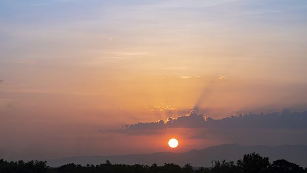 Blue and orange sunset sky with rays of sun. Natural landscape for background, early morning sky scene