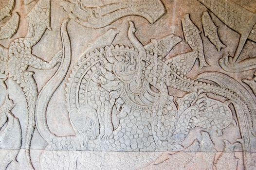 Ancient Kymer carving of the creation of the world with god fighting demons A Chinese Lion is fighting a crocodile. Churning of the Ocean of Milk gallery, Angkor Wat, Siem Reap, Cambodia.