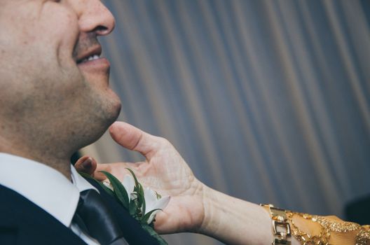 Hand of mother arranging son tie for wedding