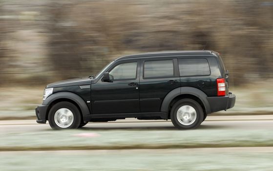 A panning shot of a speeding SUV