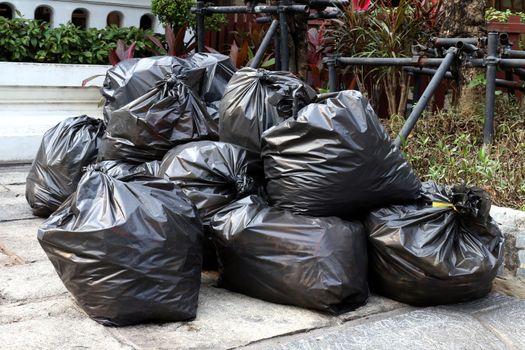 waste lots pile of garbage black bags plastic stack on the floor ground public park, many dump black garbage plastic bags stack