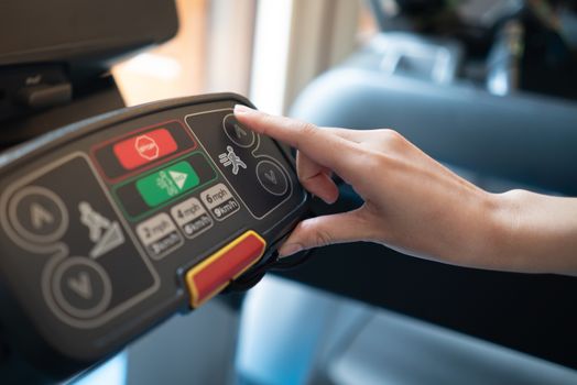 closeup of young woman athlete running on treadmill in gym. push on control panel