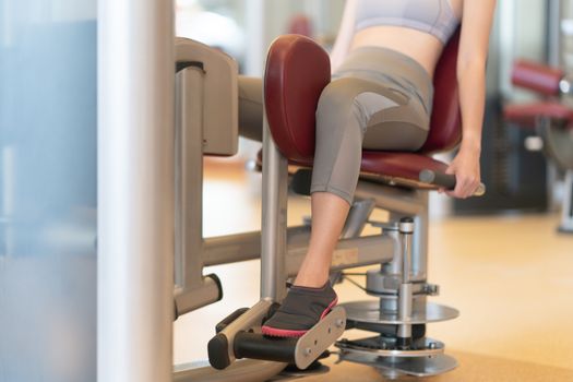 Fit woman using weights machine for her legs at the gym