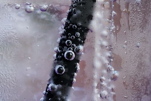 Close up glass of cool water with straw and bubbles.