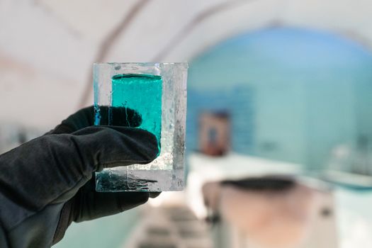 Cocktail short glass made of ice in hand. In Igloo ice bar in winter season.