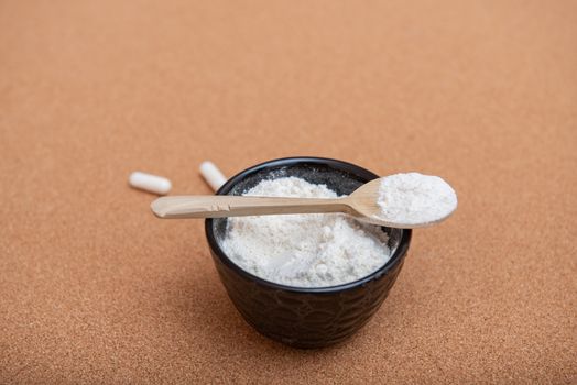 Collagen powder on a wooden spoon with empty place for text